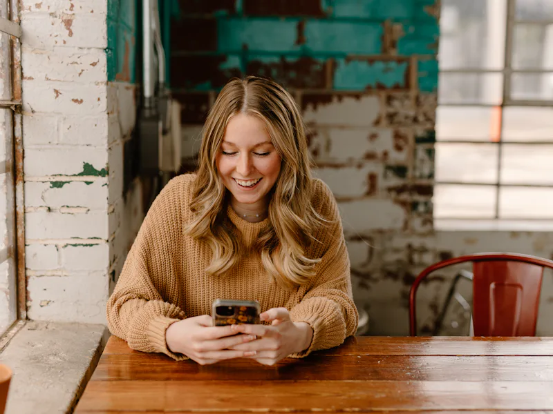 Woman sitting at a table looking at her phone