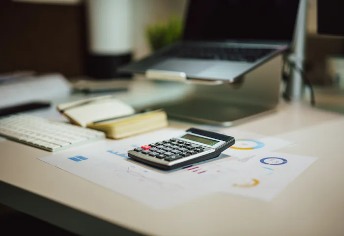 Calculator on a table next to a laptop